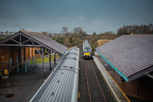 Two diesel trains are crossing at ballymoney train station in northern ireland. Looking towards the trains and train tracks from the pedestrian overpass.