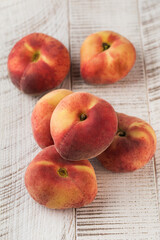 Juicy ripe flat peaches on a white wooden background. Healthy eating, fruits.