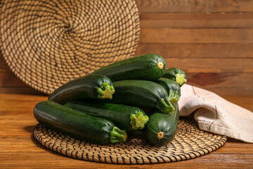 Wicker mats with many fresh zucchini on brown wooden background