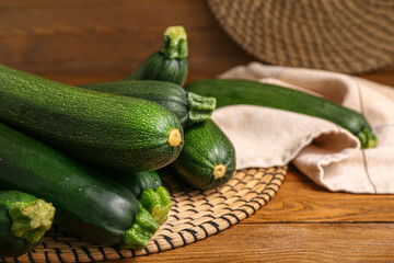 Wicker mats with many fresh zucchini on brown wooden background