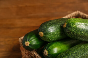 Wicker basket with fresh zucchini on brown wooden background