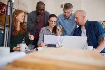 Young and diverse group of architects going over building plans together in a modern company office