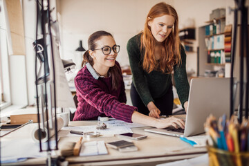 Two young female architects working on building plans together in a modern company office