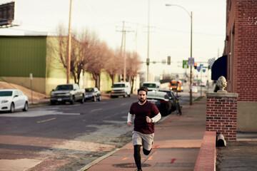 Young Caucasian man jogging on a sidewalk in the the city in the US