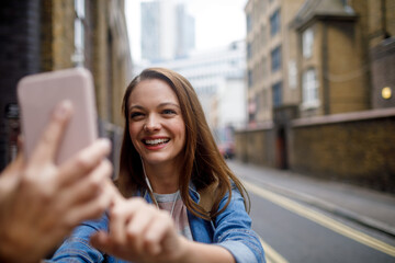 Young Caucasian woman taking a selfie on her smartphone on the streets of London UK