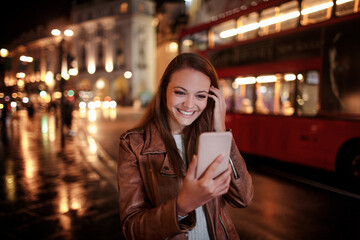 Young Caucasian woman showing the scenery of London at night via a video call on her smartphone