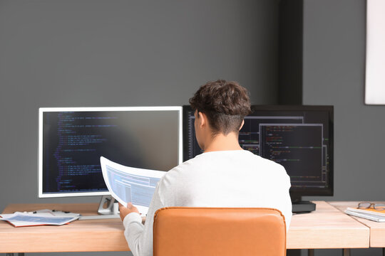 Male programmer working with computer at table in office, back view