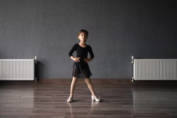 Photo sur Plexiglas École de danse Child girl standing in black sport bodysuit in dancing studio during training posture. 4 5 years old preschool age. Healthy physical development 
