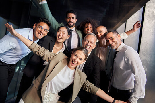 Portrait of excited funny multi-ethnic staff people business team stand in office looking at camera. Happy diverse professional colleagues group celebrate success win victory reward at corporate party