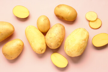 Cut and whole raw potatoes on pink background