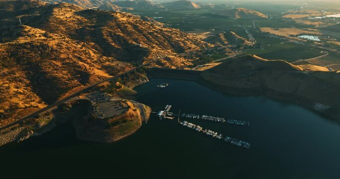 Beautiful lake with dock for yachts and boats surrounded by mountains in California. Lovely green valleys behind the rocks at backdrop.