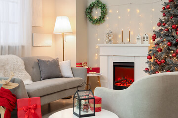 Fototapeta premium Interior of festive living room with fireplace, grey sofa and Christmas tree