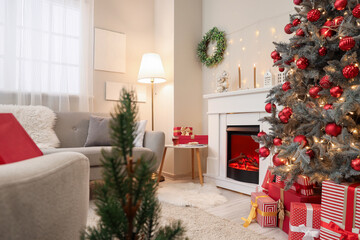 Interior of festive living room with fireplace, grey sofa and Christmas tree