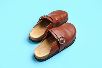Pair of leather orthopedic slippers on color background