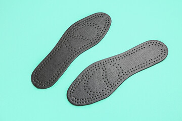 Pair of black orthopedic insoles on color background