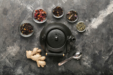 Fototapeta na wymiar Composition with teapot, different types of tea and infuser on grunge background