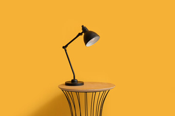Small table with lamp near yellow wall