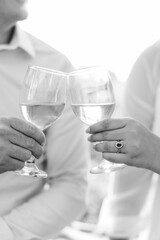 A couple in love clinks wine glasses together in a close-up portrait in black and white.