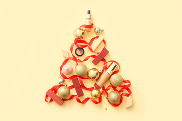 Christmas tree made of golden balls, makeup cosmetics and ribbon on beige background
