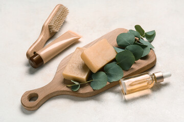 Composition with cosmetic products, massage brush and eucalyptus branch on light background