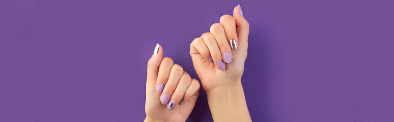 Beautiful groomed womans hands with matte lavender nail design on purple background. Manicure,...