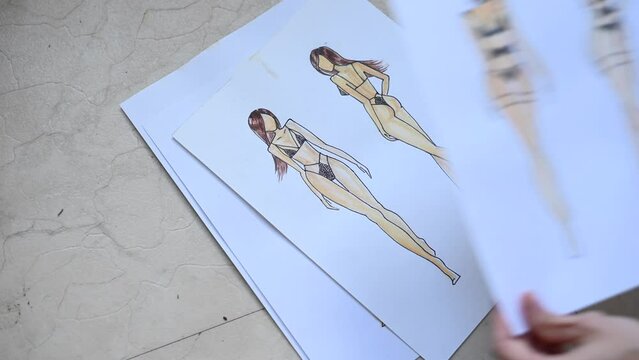 Woman looking at sketches of underwear. 