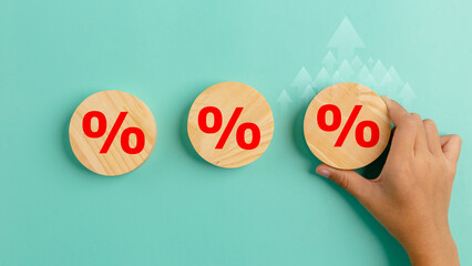 Interest rate finance and mortgage rates concept. Hand holding wooden circle with percentage sign arrow rise, financial growth, interest rate increase, inflation, sale price and tax rise concept. - obrazy, fototapety, plakaty