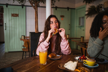 Young woman having brunch with her friends on sunday. She is eating a salmon bagel sandwich.