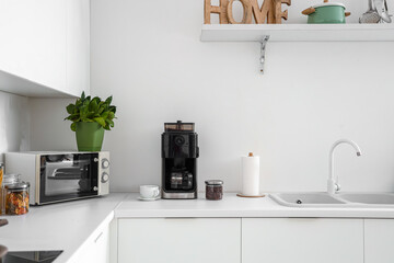 Interior of modern kitchen with coffee machine on white counter
