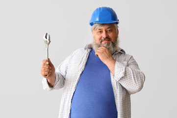 Portrait of senior man in hardhat with wrench on grey background. Labor Day celebration