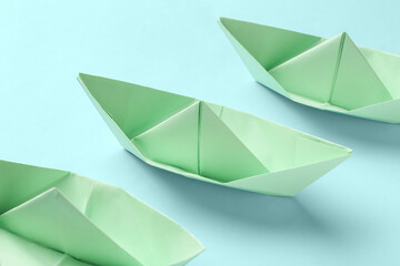 Green origami boats on blue background