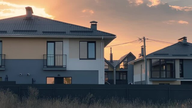 Newly built gated community with a group of homes and duplexes built together as a single development for sale in suburbia at summer sunset