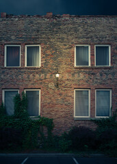 Fototapeta na wymiar Old brick facade with single light and dark windows