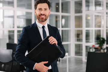 Fototapeta premium Happy real estate agent with leather portfolio indoors. Space for text