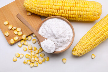 Bowl with corn starch, ripe cobs and kernels on white marble table, flat lay