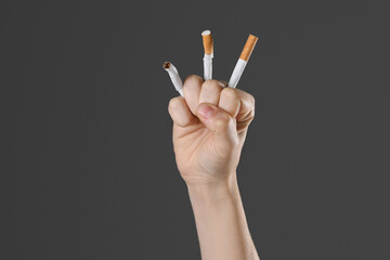 Stop smoking concept. Woman crushing cigarettes on gray background, closeup with space for text