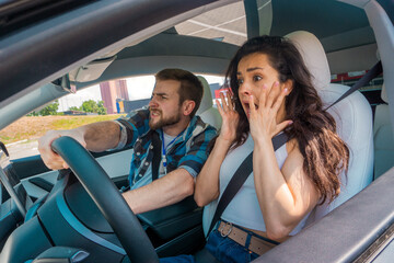 Young lady screaming and keeping his hands in the air while instructor keeping his hand on the steering wheel. Traffic accident. Driving test, driver courses, exam concept