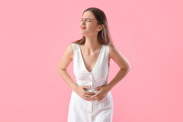 Young woman suffering from stomach ache on pink background