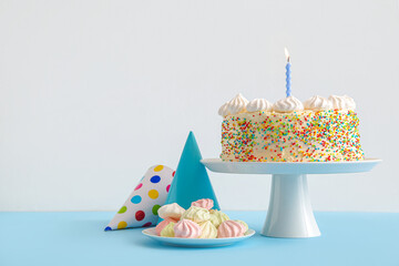 Stand with yummy Birthday cake, party cones and meringue on color background © Pixel-Shot