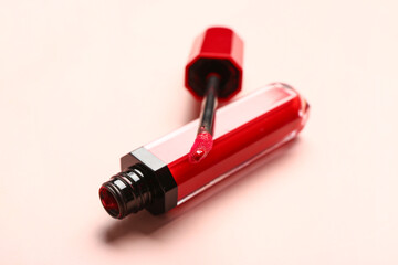 Stylish red lipstick with brush on beige background, closeup