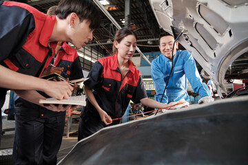 Asian male professional automotive supervisor advises and inspects a mechanic worker woman about...
