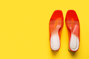 Stylish orange sandals on yellow background