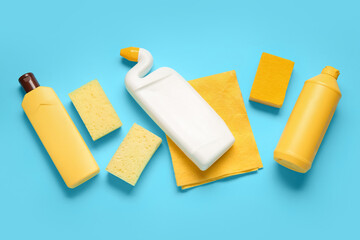 Bottles of detergent and sponges on blue background