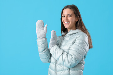 Young woman in winter clothes on blue background