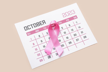 Pink ribbon with calendar on beige background. Breast cancer awareness concept