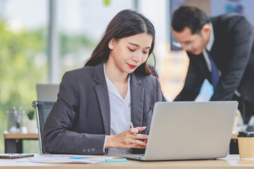 Obraz premium Portrait shot of Asian professional successful female businesswoman secretary employee in formal suit sitting smiling look at camera typing laptop notebook computer at working desk in company office