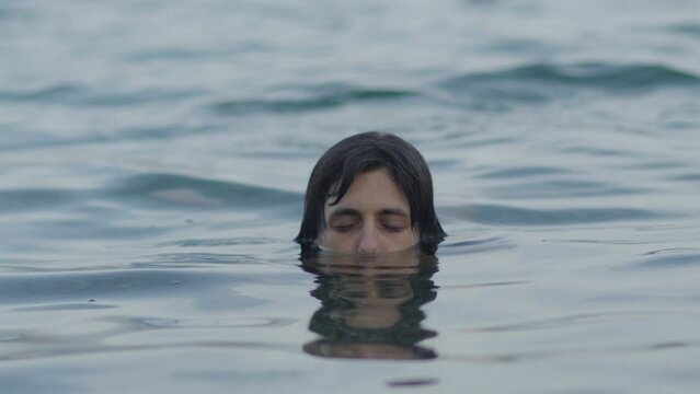 Female in sea water, with half face under the water.