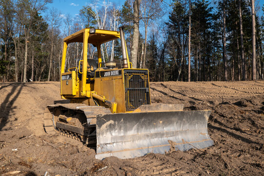 CROW WING CO, MN - 10 MAY 2023: Older John Deere Bulldozer with front blade and hydraulics power, parked on a new home construction building site plot of land.