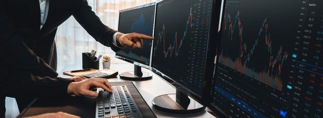 Group of traders discussing on office desk, monitoring stock market on monitor at office workplace. Businessman and broker analyzing stock graph together at stock trading company. Trailblazing - obrazy, fototapety, plakaty