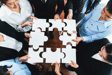 Top view multiethnic business people holding jigsaw pieces and merge them together as effective...